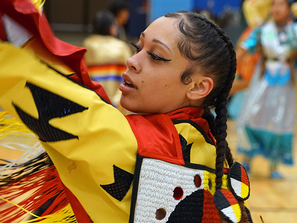 A female dancer holds up her arm during a judged competition at the 2023 Powwow