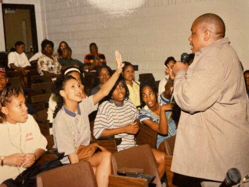 Old photo of George Davis talking with students as one student raises their hand