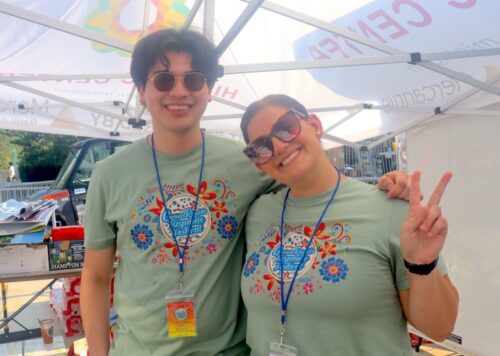 Alexis and his colleague posing in a tent during the Grand Rapids Hispanic Festival