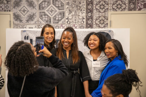 Erika Alexander posing with students, faculty, and staff for a photo