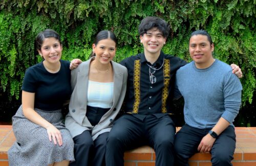 Photo of Alexis with three of his friends sitting on a brick wall