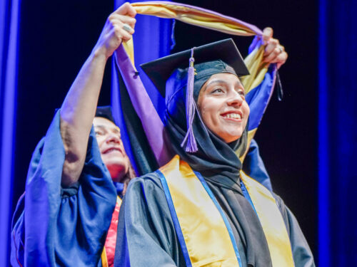 A master's student is hooded during a graduation