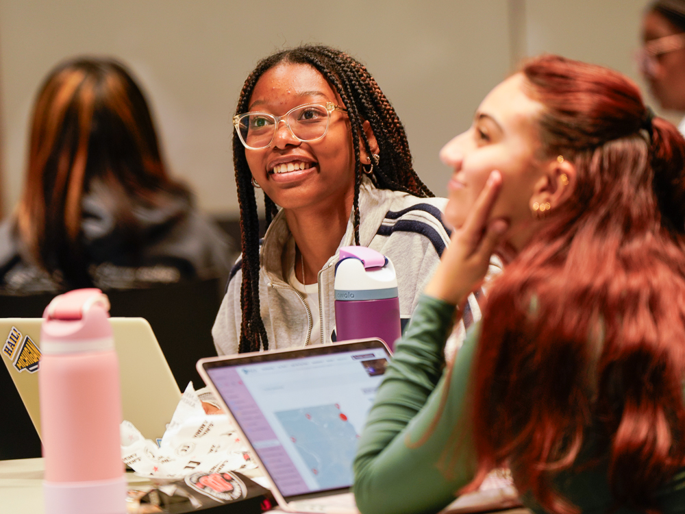 A smiling student looks at a instructor