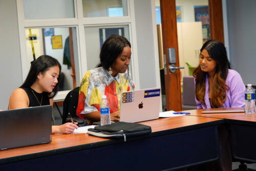 A group of graduate students work together at a laptop