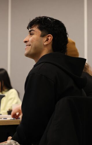 Nicholas Velazquez smiles and wears a black hoodie