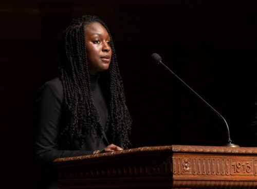 Yacine Lo stands at the Hill Auditorium lectern in a black sport coat